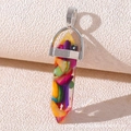 Macro shot of a bullet-shaped resin pendant filled with colorful fragments on a textured base - Resin Mixed Color