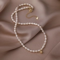 Detalle del collar de perlas de agua dulce con colgante de corazón dorado en seda champán - Estilo de Colgante de Bola Pequeña Dorada