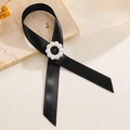 Detail einer eleganten schwarzen Schleifenbrosche mit Perlenring auf strukturiertem Stein - Schwarzes Band Perlenkreis