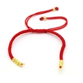 Detail of adjustable red braided rope bracelet with small gold beads on white background - Red