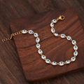 Bracciale a catena occhio di Allah dorato con ciondoli blu su sfondo legno scuro - Bianco