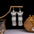 Ethnic silver-finish butterfly tassel earrings displayed on a minimalist wooden stand - Butterfly Hollow Flower Disc Tassel Style (E3037-5)