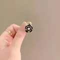 Elegant small black camellia hair claw clip with gold trim and white pearl accent - Camellia