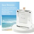 Marine reed diffuser in glass bottle on white podium with beach scenery backdrop - Sea Breeze
