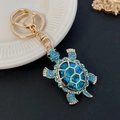 Squisito portachiavi tartaruga dorata con un grande cristallo blu e piccoli strass azzurri - Blu