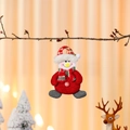Detail of plush snowman ornament with red hat and button details hanging on tree - Snowman