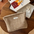 Detail of wool tweed cosmetic bag with woven label on a rustic wooden table setup - Camel