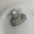 Macro shot of silver metallic heart-shaped hair claw clip on a white decorative dish - Grey Silver - Heart/Ponytail Clip