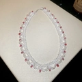 Dettaglio della collana in pizzo con perle bianche e ciondoli a goccia rossi su superficie - Stile Pendente a Goccia Rossa / Bianco-Rosso