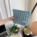 Blue bubble textured makeup bag with Sozakka label held over a tidy workspace - Bubble Blue