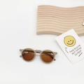 Close-up of beige round kids sunglasses on a wooden stand with a cute decorative card - Gray