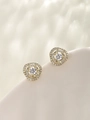 Detalle macro de pendientes de flor dorada con circonitas blancas y piedra central - Chapado en oro de 14 quilates