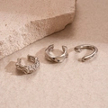 Vista de tres ear cuffs plateados con textura de lava sobre una superficie de piedra natural - Estilo Irregular con Textura de Lava / Plata (Juego de 3 piezas)