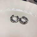 Close-up of silver irregular hammered geometric stud earrings on a beige ceramic plate - 62# Silver Irregular Hammered Design Earrings (62# Ear Clip-Silver)
