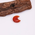 Polished red agate crescent moon pendant displayed on a natural wood bark background - Red Agate