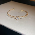 Detalle del brazalete abierto dorado con flor de circonita y piedras de corte baguette - Pulsera Geométrica de Circón Dorado