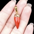 Red bullet shaped jasper pendant with gold plated bail held by hand for scale - Red Jasper