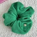 Detail of green terry cloth headband featuring a small circular handmade metal tag - Scrunchie / Green
