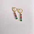 Gros plan de boucles d'oreilles dorées avec pierres zircons colorées sur cuir blanc - Or + Multicolore (DEK1764)
