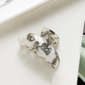 Dettaglio di una piccola molletta per capelli marmorizzata su superficie bianca - Grigio