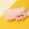 Close-up of pink leather long wallet with golden heart buckle held by a hand - Light Pink