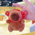 Detail of plush capybara keychain with red festive hat shown in hand against ball pit - God of Wealth Dark Brown + Bead Chain