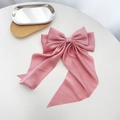 Detailopname van een grote roze satijnen harikstrik met elegante lange linten op een bureau - Roze