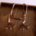Macro detail of irregular glass beads and natural stone tassels on a wooden tray - White-Coffee