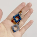 Blue marble acrylic square earrings with gold finish metal hoop on model hand - Square Fog Blue (Silver Hoop)