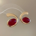 Macro-opname van gouden oorbellen met grote rode ovale edelstenen op een reflecterend vlak - Zilveren Naald Oorbellen-Goud-Rood-Large