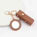 Detailed view of brown leather lipstick keychain with gold hardware and small round mirror - Coffee