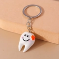 Portachiavi a forma di dente bianco con fiore arancione e viso sorridente su sfondo beige - Rosso