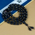 Macro detail of 108 black wood prayer beads with gold spacers on a vintage book - 7mmx9mm Bamboo Shape Beads * 66Pcs