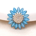 Dettaglio macro di accessorio a fiore azzurro con base dorata e strass scintillanti - Blu