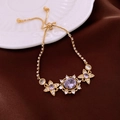 Nahaufnahme eines vergoldeten Armbands mit violettem Edelstein und klarem Strass - Armband / Gold-Lila