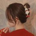 Golden metal bunny hair claw with red bow and rhinestones shown on model hair - Gold Rhinestone Rabbit Claw