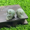 Mini natural green stone crystal skulls with black inclusions on a wooden base - Kiwi