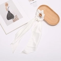 Detail of ivory satin scrunchie with long ribbons on elegant wooden tray setup - White