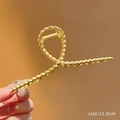 Pince à cheveux en métal doré mat 11,5 cm de long tenue en main vue rapprochée - 73# Torsion Croix