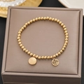 Macro detail of gold beaded bracelet featuring Chinese Fu and Double Happiness pendants - Gold Fu Xi Bead Elastic Style (5156)
