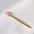 Detailweergave van een gouden metalen balpen met een roze kristallen steen erop - Rozenkwarts