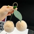 Cute cherry keychain with beige faux fur pom poms and green leather leaves on gold ring - Nude