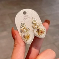 Macro detail of heart-shaped earrings with real dried flowers and white pearls - Starlight Heart Dried Flower