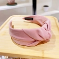 Close-up of pink fabric headband featuring a stylish top knot and handmade woven label - Pink