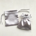Macro detail of two grey satin drawstring bags showing smooth texture and ribbon bow tie - 12x14cm / Silver Gray