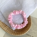 Pink satin scrunchie with elegant pleated texture on a decorative straw background - Nude Pink