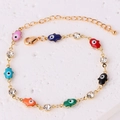 Dettaglio di bracciale a catena dorata con ciondoli Hamsa in smalto colorato e cristalli - Bracciale Mano di Fatima con Strass