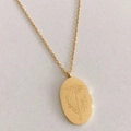 Gold oval pendant necklace featuring delicate December flower engraving on a thin chain - April Daisy