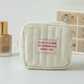 Close-up of minimalist quilted square cosmetic pouch with orderly way text label - Off White