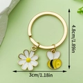 Golden keychain featuring a yellow enamel bee and a white daisy pendant with size labels - Double Pendant Daisy Bee